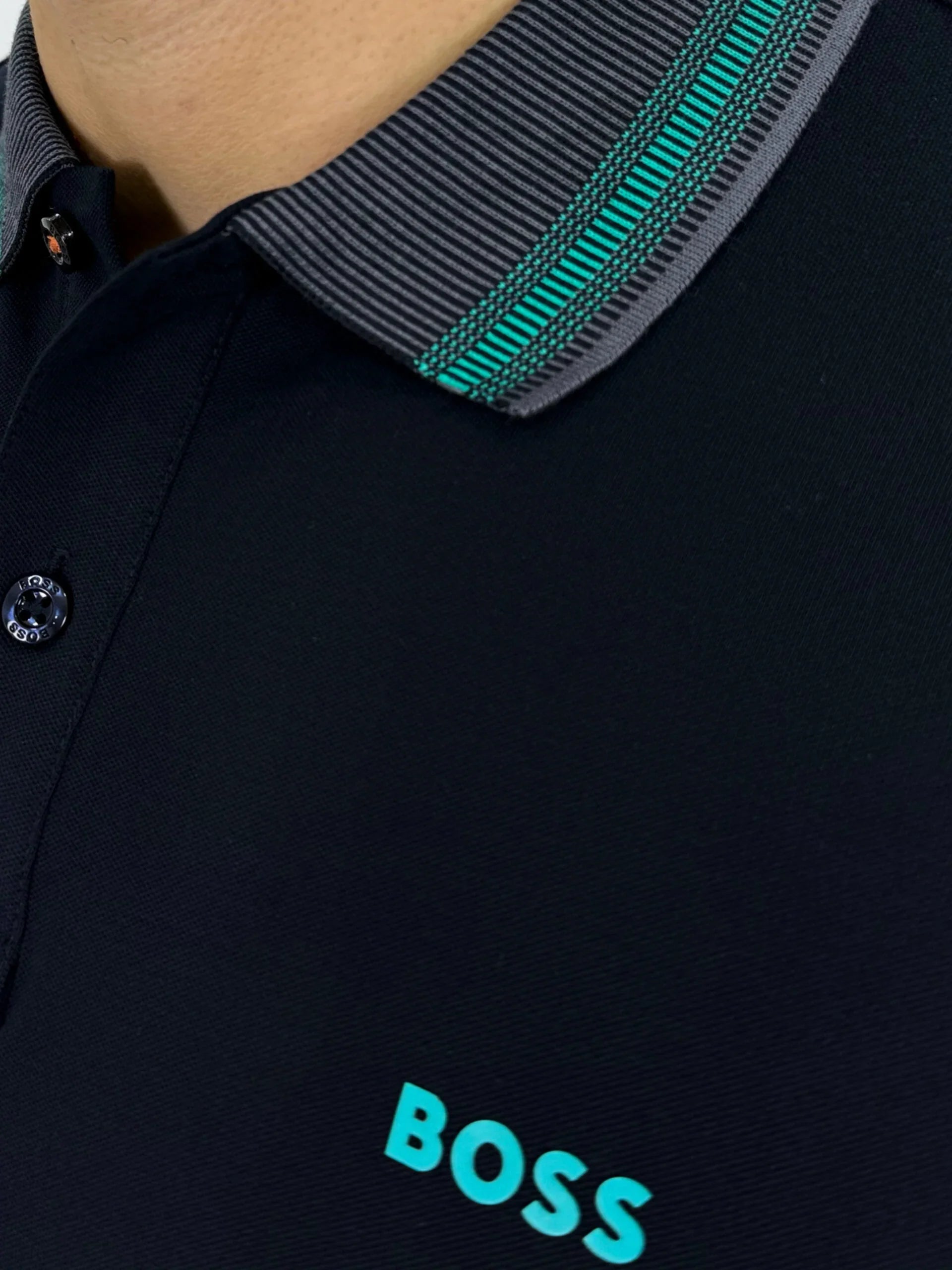 Camisa tipo polo negra con cuello rayado y logo BOSS en turquesa, estilo moderno para hombre