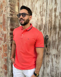 Hombre con camisa polo roja, gafas de sol y pantalón blanco, estilo urbano y moderno para hombre