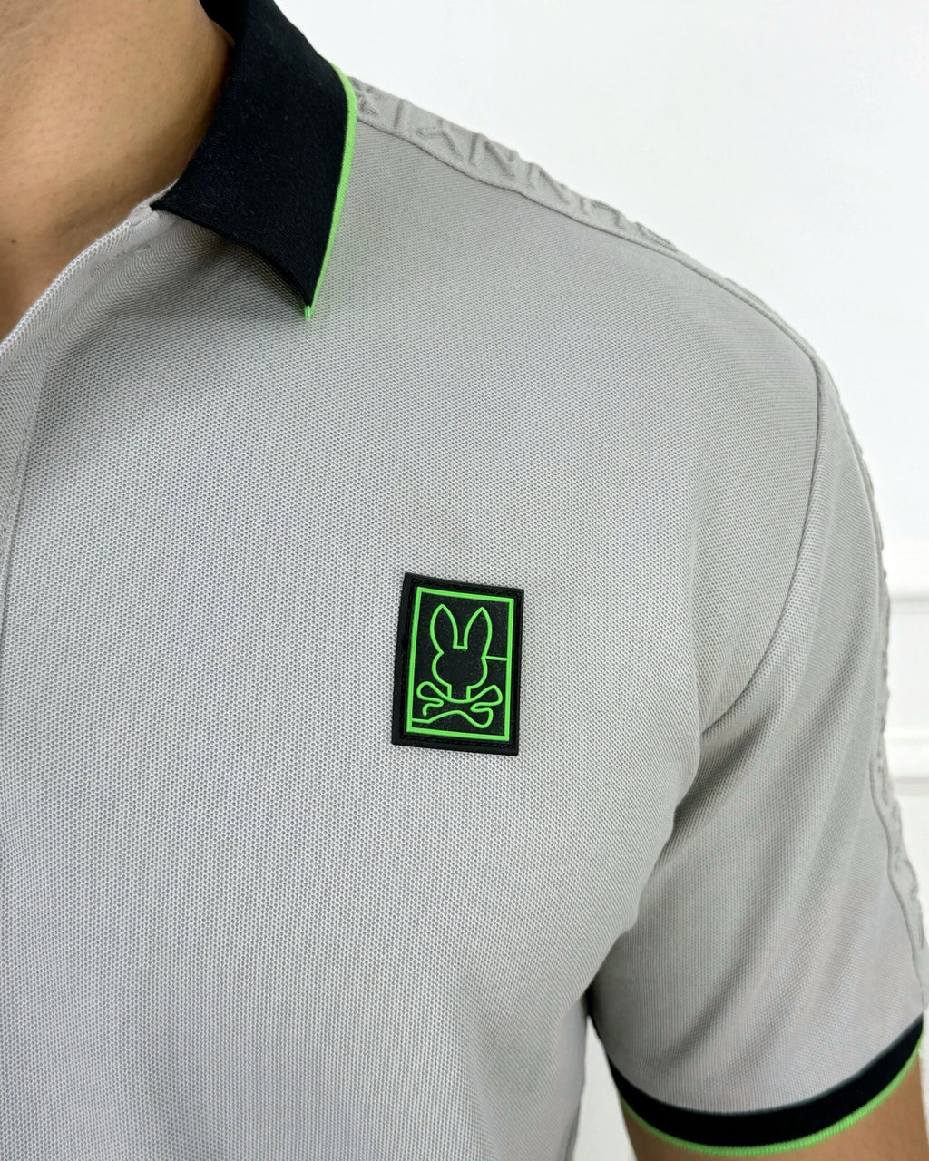 Camisa polo gris con cuello negro y detalles neón verde, ideal para hombre con estilo moderno y calidad premium.