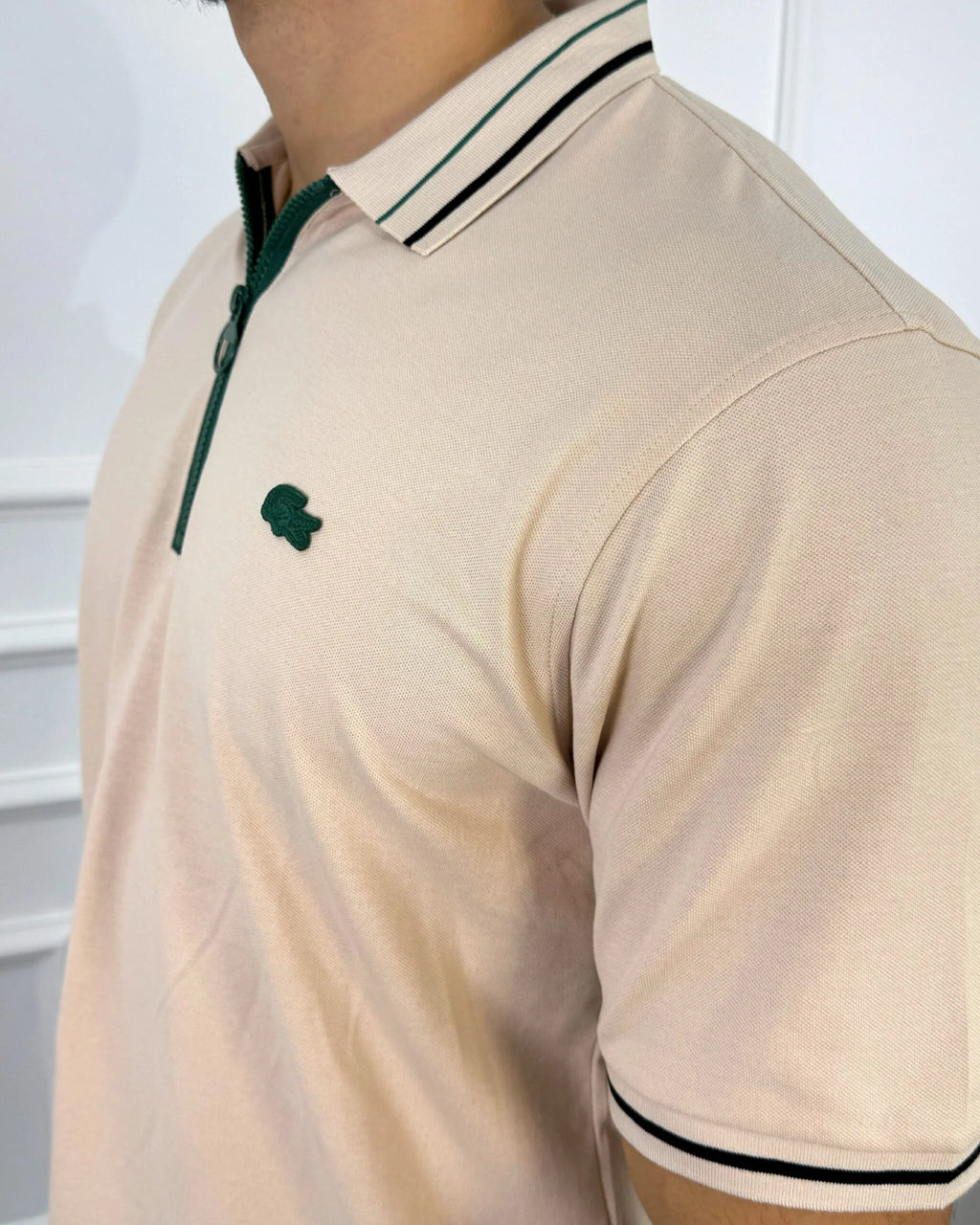 Camisa tipo polo beige con cierre verde y detalles en negro, estilo moderno y premium para hombre