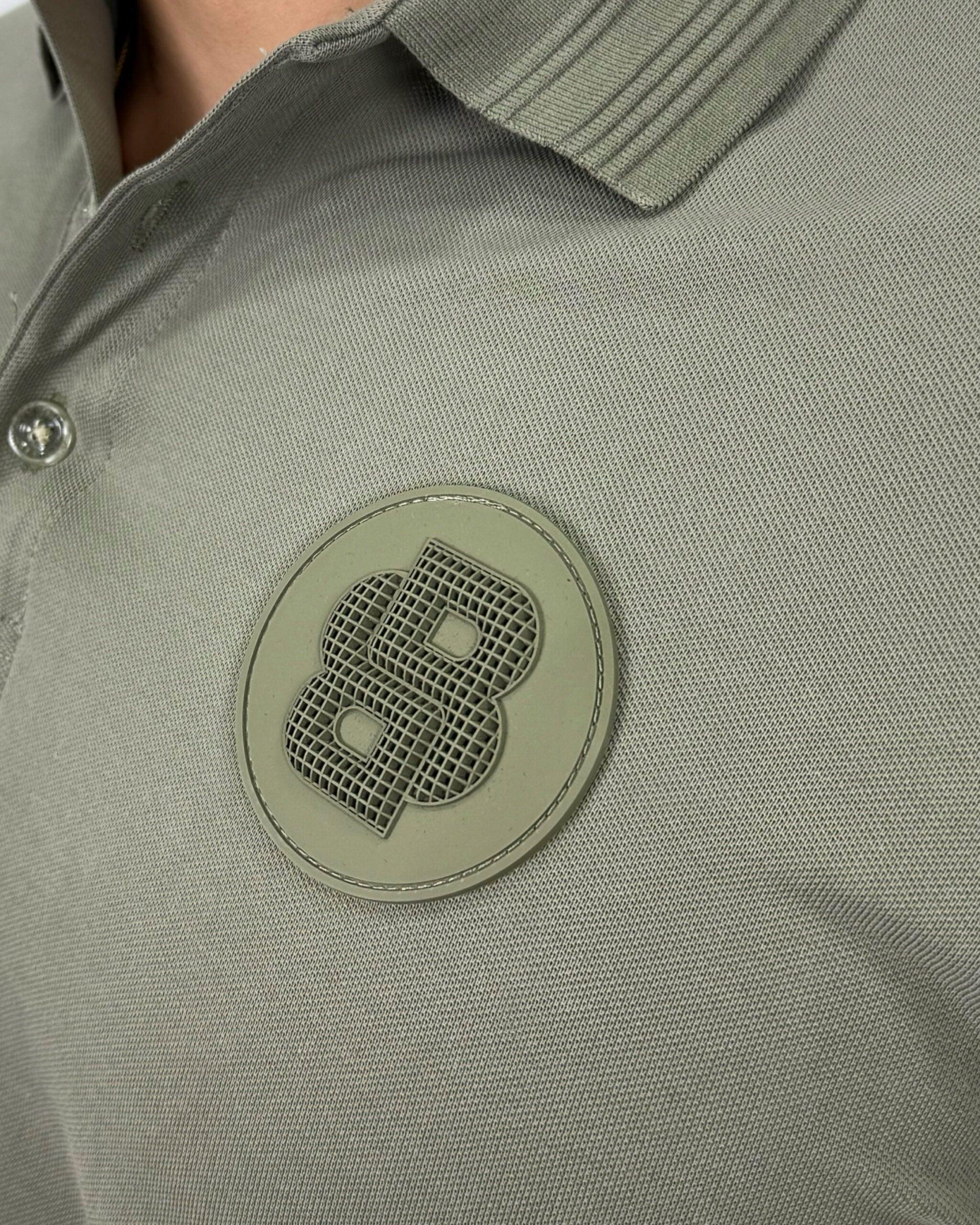 Camisa polo hombre gris con logo texturizado, cuello ribeteado y botones, estilo moderno y calidad premium